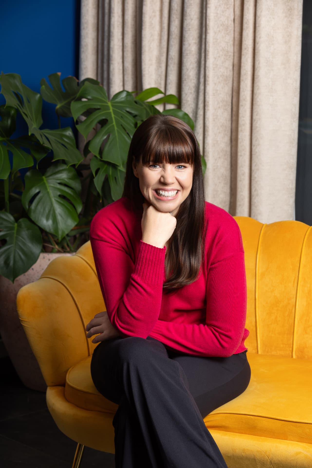 Brianne West seated in a mustard velvet chair